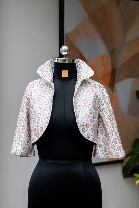 A white sequin jacket displayed on a mannequin, featuring short sleeves and a round neckline.